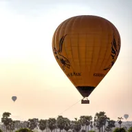Hot-air balloon above palm trees in the morning light