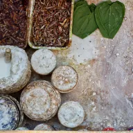 Market stall from above: pieces of betel nut, betel leaves and round tins