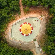 White stupa in a forest clearing, from above