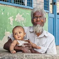 Grandfather with a baby on his lap in front of a green wall