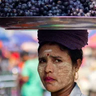 Woman with thanaka carrying a tray of grapes on her head
