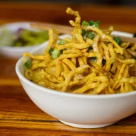 Khao soi with crispy noodles in a white bowl