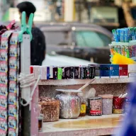 Betel stall with cigarettes and chewing gum, below it a lime pot and jars covered in white lime splashes