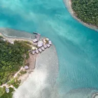 Turquoise river mouth with stilt houses, from above
