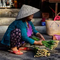 Woman with a conical hat bundling lemongrass on the street