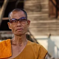 Elderly monk with glasses in an orange robe