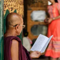 Monk with glasses reading a booklet