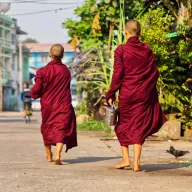 Two monks walking barefoot along a road