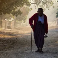 Elderly man with a walking stick on a path in the morning haze