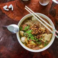 Noodle soup with herbs and chopsticks, from above