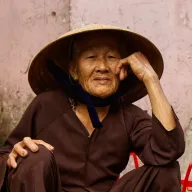Old woman with a conical hat resting her head on her hand