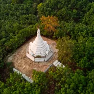 White stupa in a forest clearing, from above