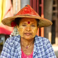 Woman with thanaka paste on her face and a red straw hat